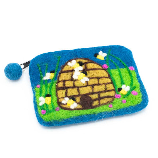 Blue felt purse with a green field with a domed beehive in the middle. Bees are scattered around the hive.
