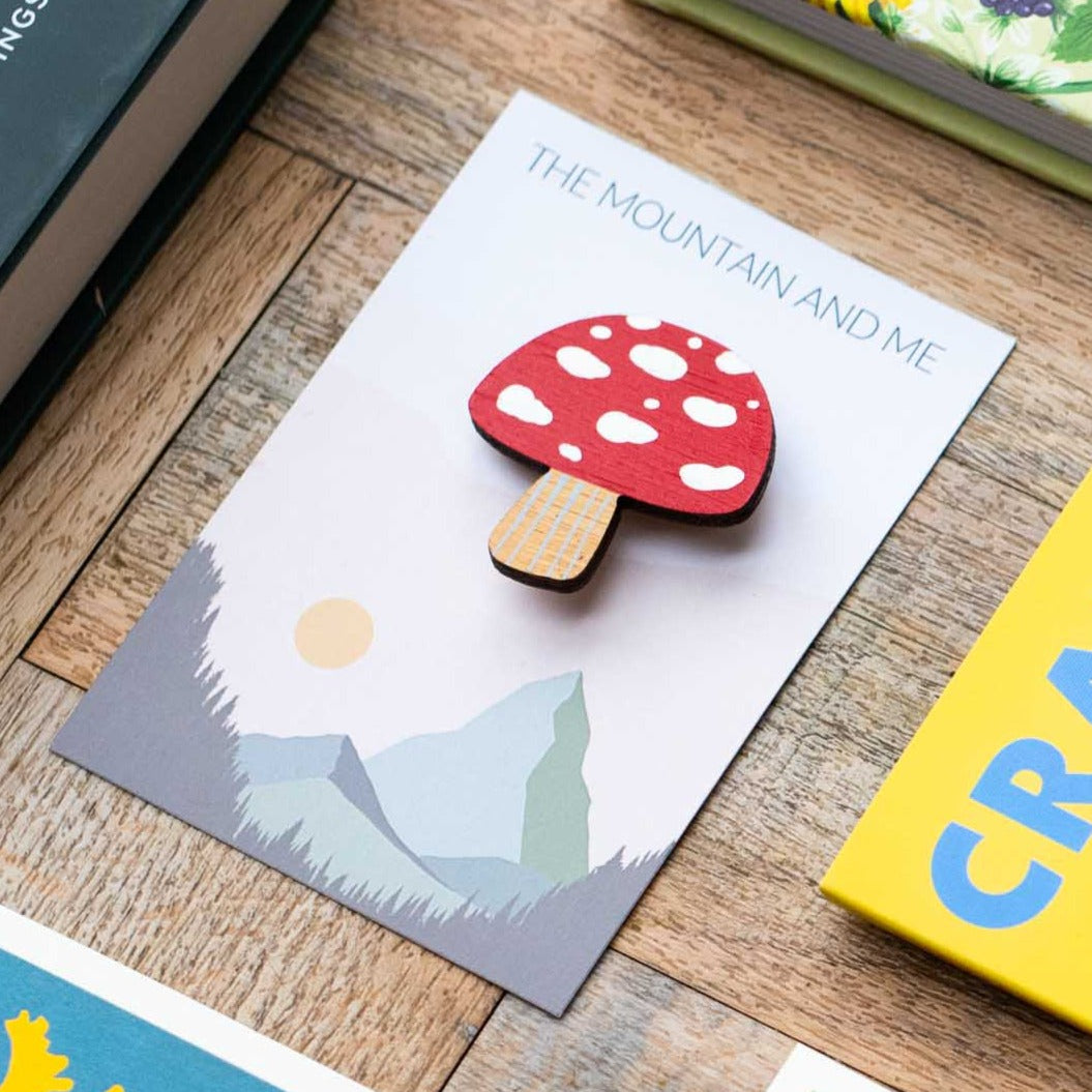 Toadstool brooch photographed on its backing card on a wooden floor