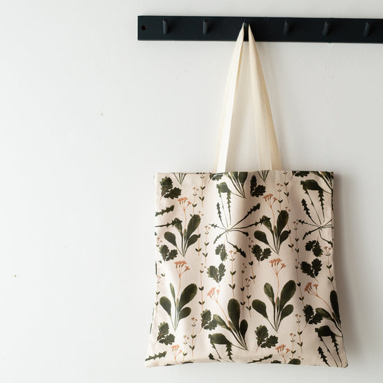 Cotton tote hanging froma black coat hanger.