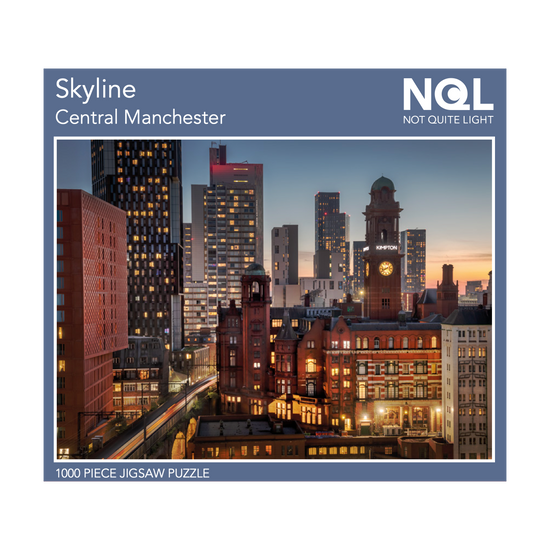 The Not Quite Light Skyline jigsaw box seen head on. The image that makes up the jigsaw is surrounded by a dusty blue border and white text with the title and NQL branding.