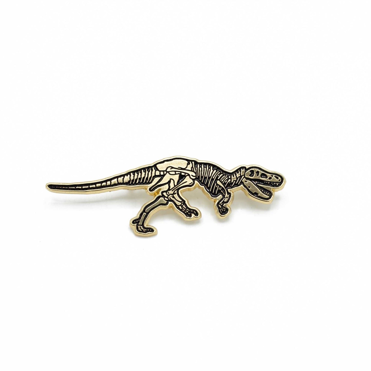 The golden enamel pin shaped as Stan the T. rex's fossil with one leg lifted in walk and the mouth open.
