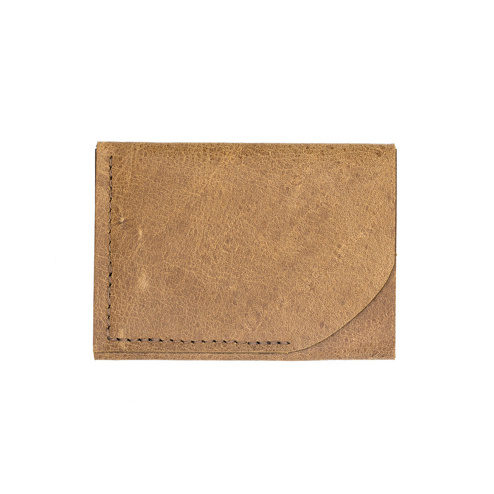 The brown leather card holder in a lying down on the long edge side view.