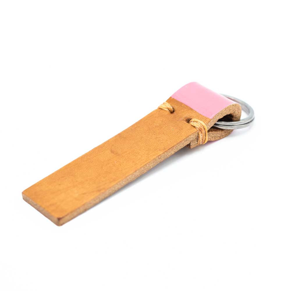 Tan leather strip keyring with dusky pink colour on the part that is folded around the ring.
