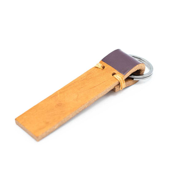 Tan leather strip keyring with dark aubergine colour on the part that is folded around the ring.
