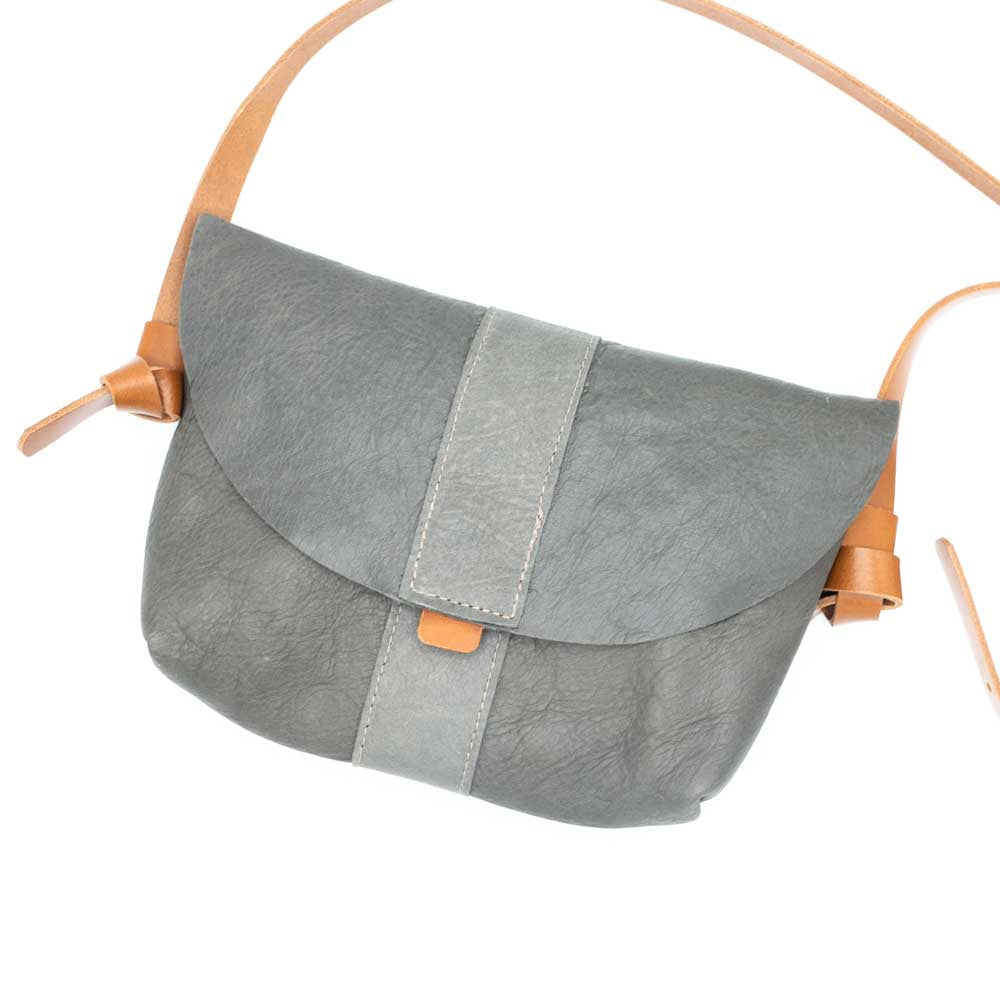 Front facing grey bag flat laid on the back with the tan leather straps at either side.