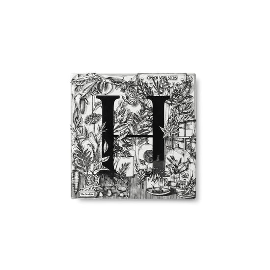 Letter H tile with the letter in black and details of flowers, weeds and foliage around the letter.