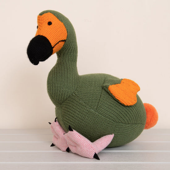 Lifestyle shot of moss green and orange dodo knitted toy.