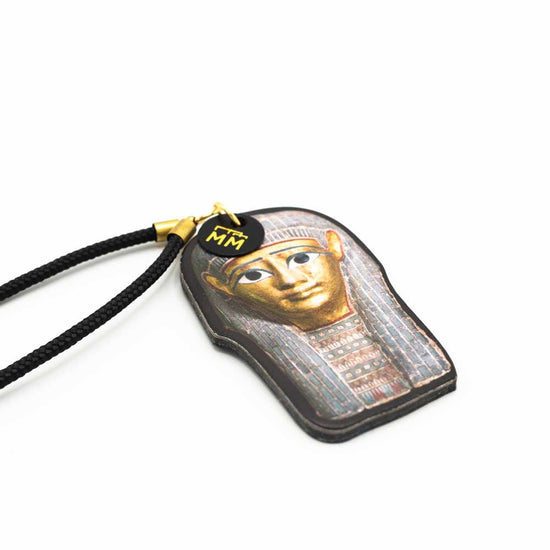 Close up slightly angled side view of burial mask photograph bag charm.