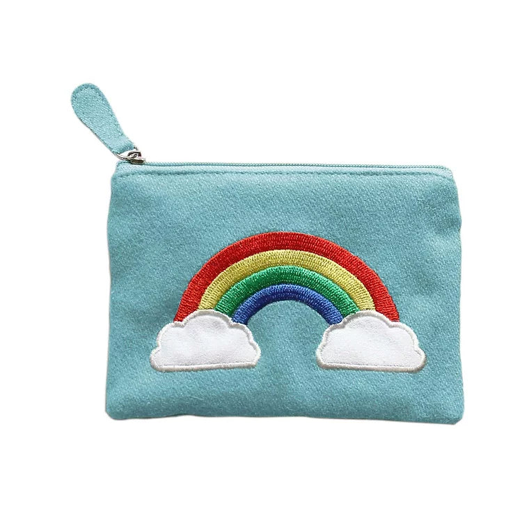 Pale blue felt purse with a full rainbow with the feet on either side buried in a small cloud. White backdrop.