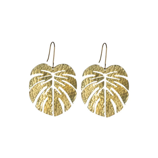 The brass earrings of a monstera leaf shape on a white background