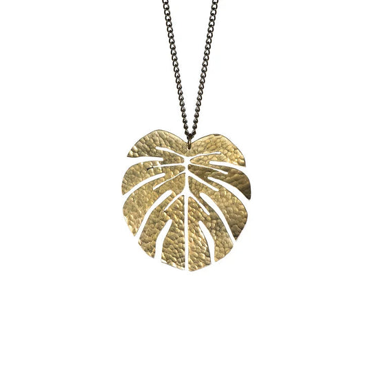 The large brass pendant shaped as a monstera leaf on a white background.
