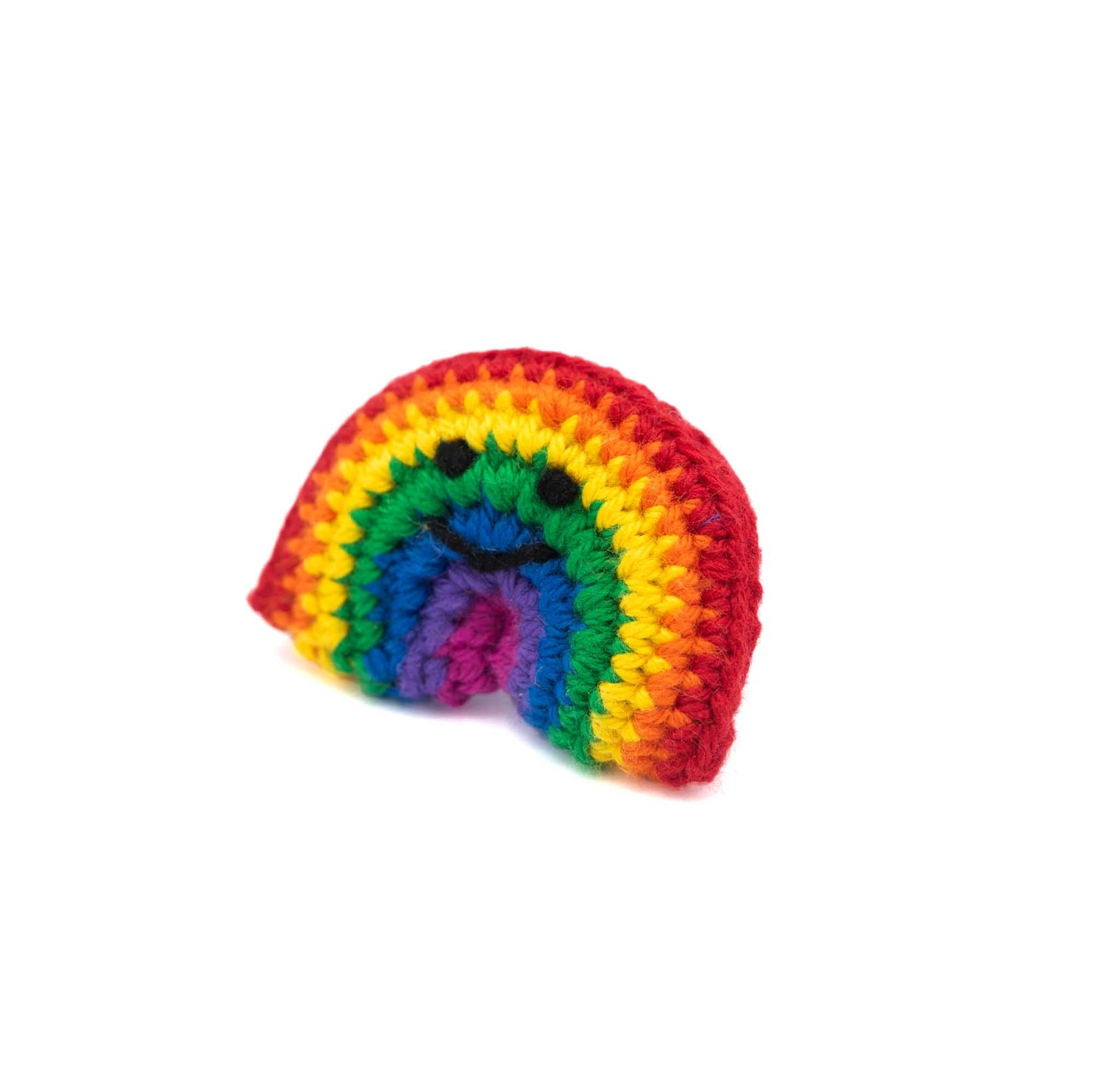 Angled view of Crochet rainbow brooch with a little smiley face in black thread.