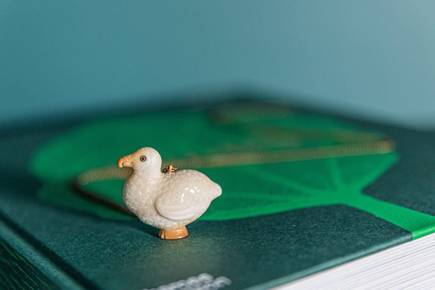 Dodo tagua necklace on a green book that blurs into the background.