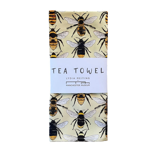 The bee tea towel folded and with the white paper belly band as it appears when packaged.