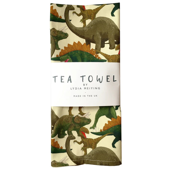 The dinosaur tea towel folded and with the white paper belly band as it appears when packaged.