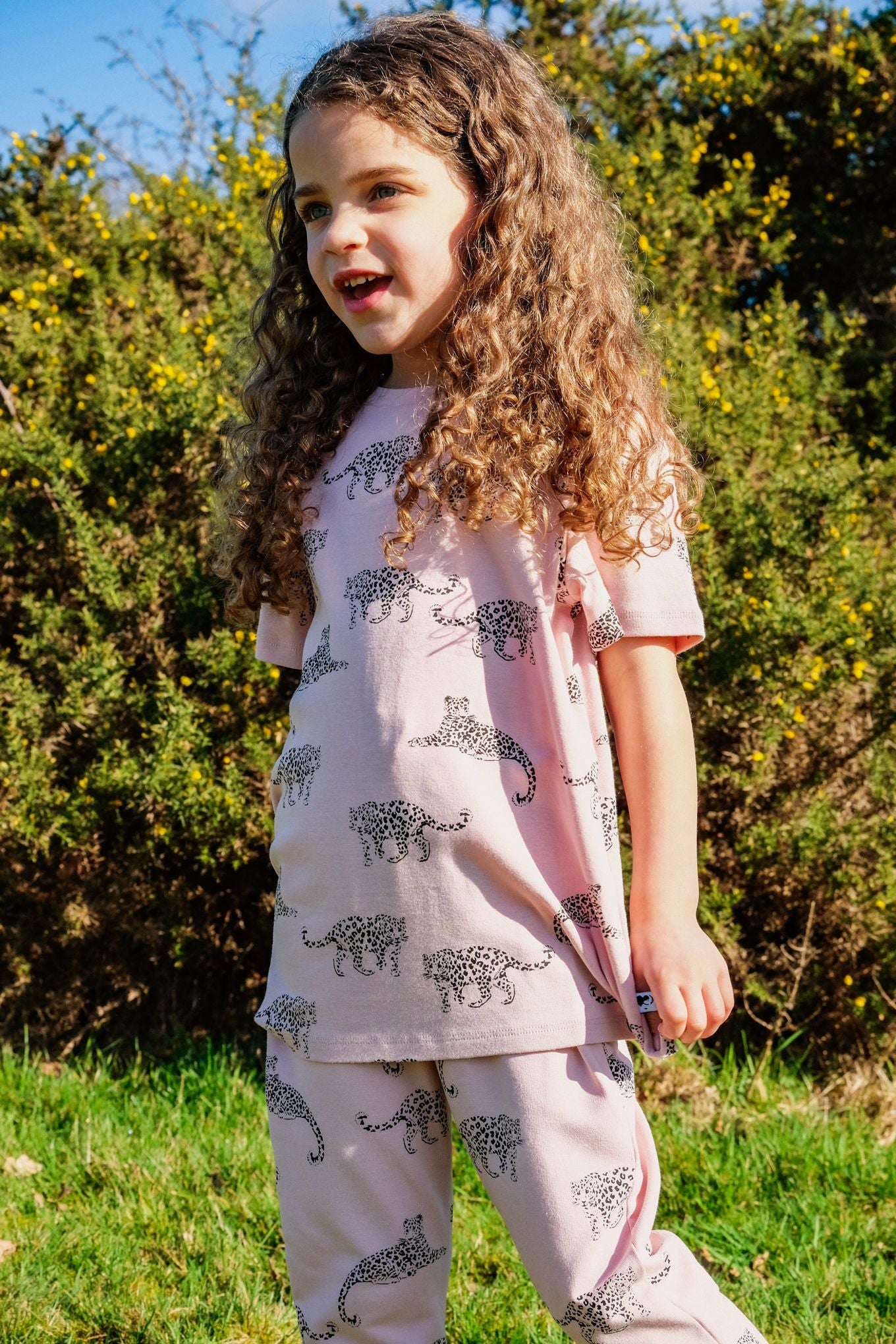 Lifestyle shot of child wearing both the t-shirt and leggings of the leopard print clothing range.