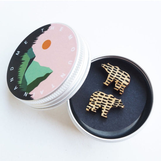 Load image into Gallery viewer, The bear earrings inside the screw top tin. The lid is resting against the side of the open tin and has the mountain and me branding on it.
