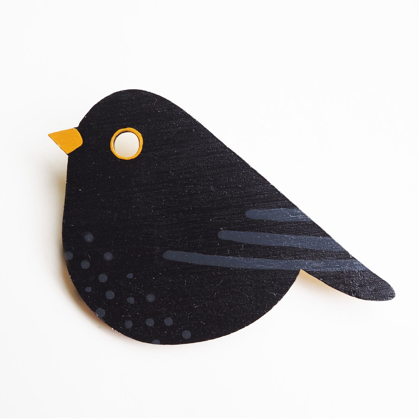 Painted blackbird brooch against a white background.