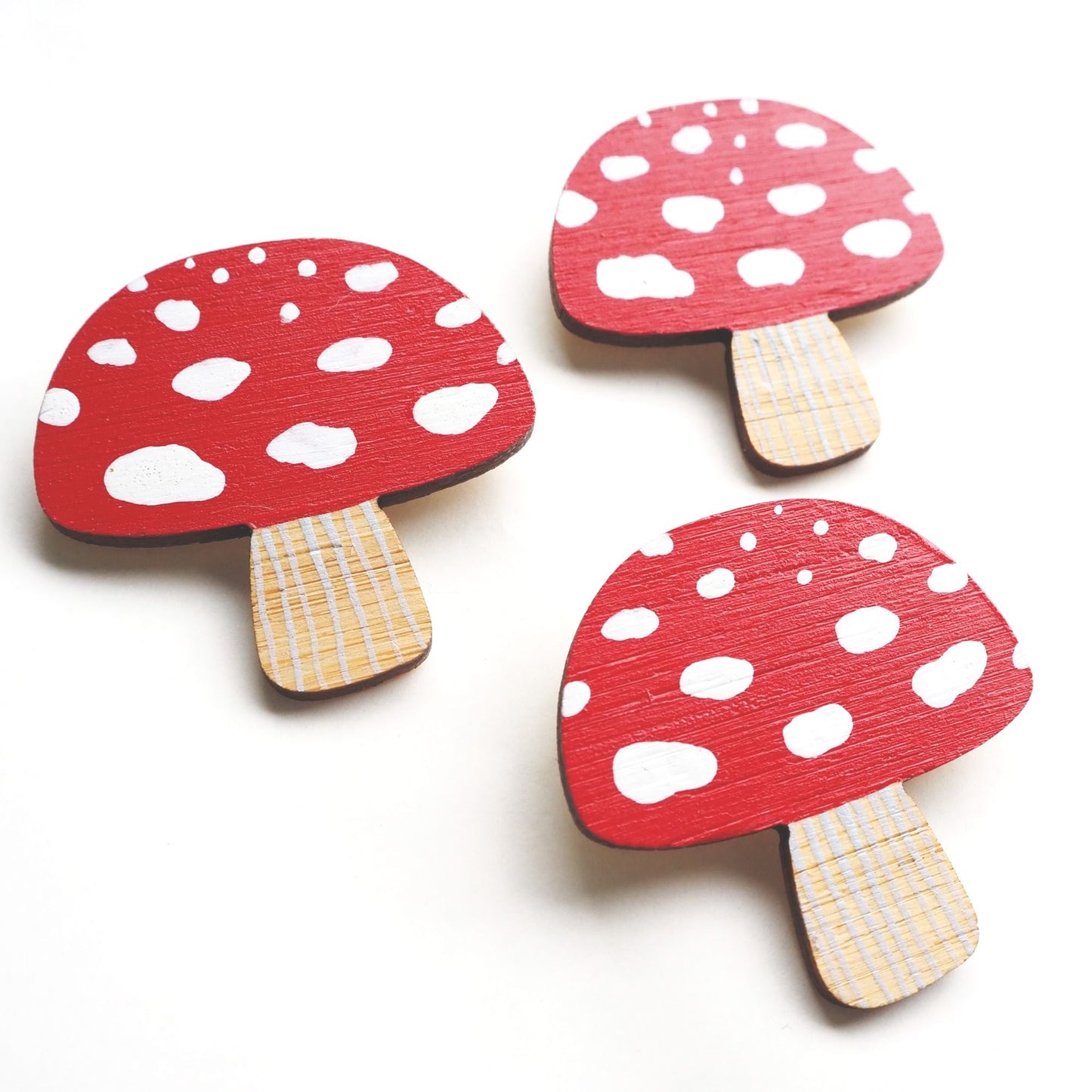 Three toadstool brooches arranged in a triangle on a white background.