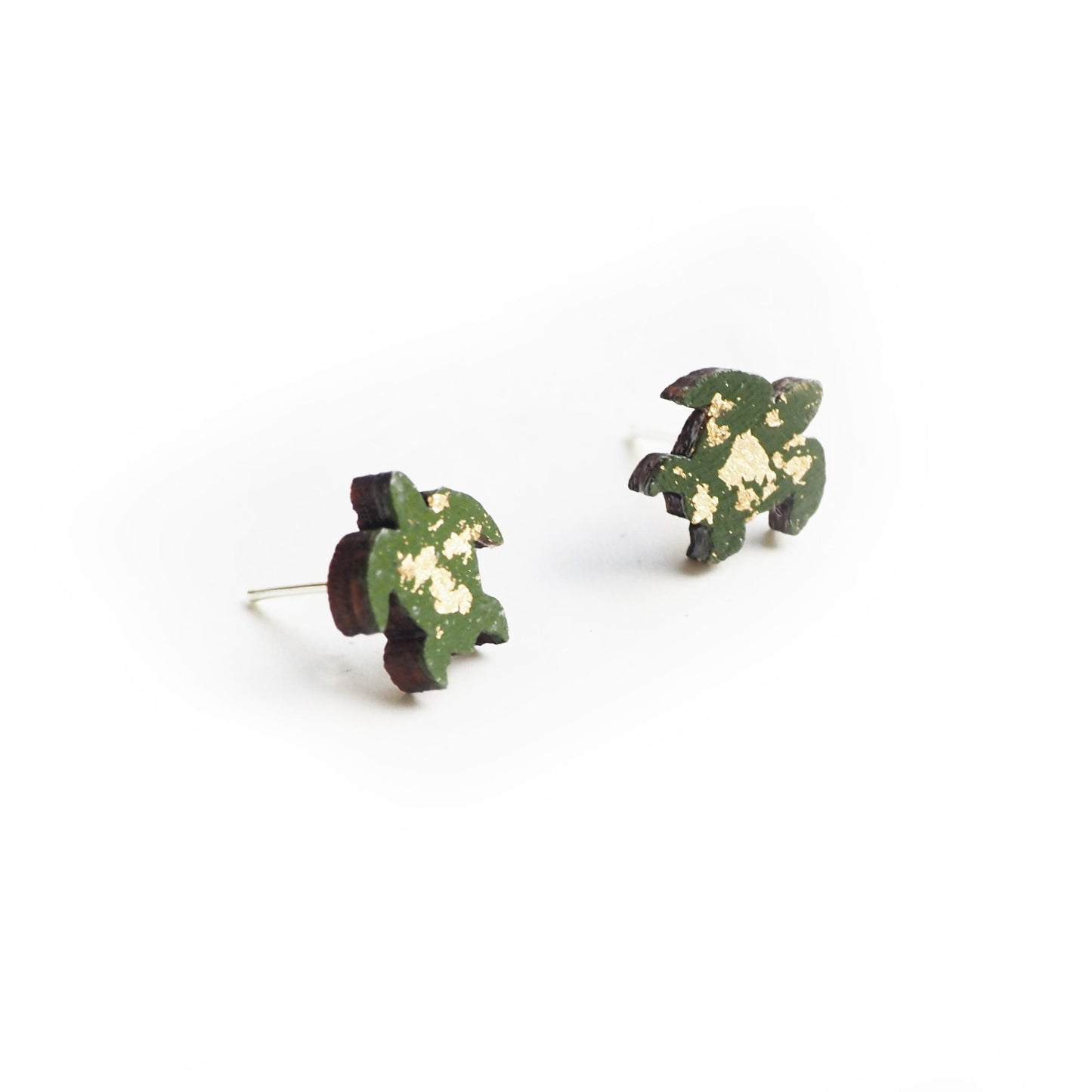 The turtle earrings resting on a white surface.