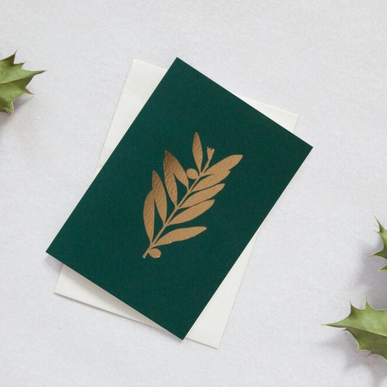 Dark green card with a brass foil olive branch motif.