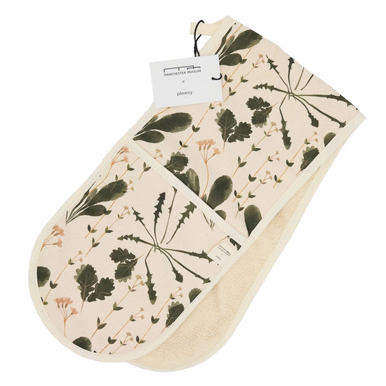 Wilding print oven gloves folded and with the white card swing tag attached at the top. White background.