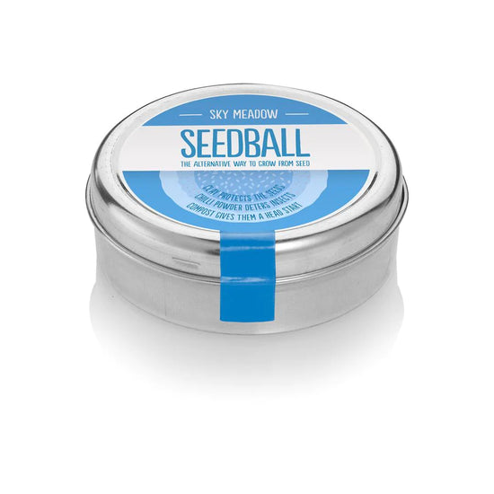 The sky mix tin with a blue sticker on top with blue and white sans serif font saying, Sky Meadow, Seedball, The alternative way to grow from seed.