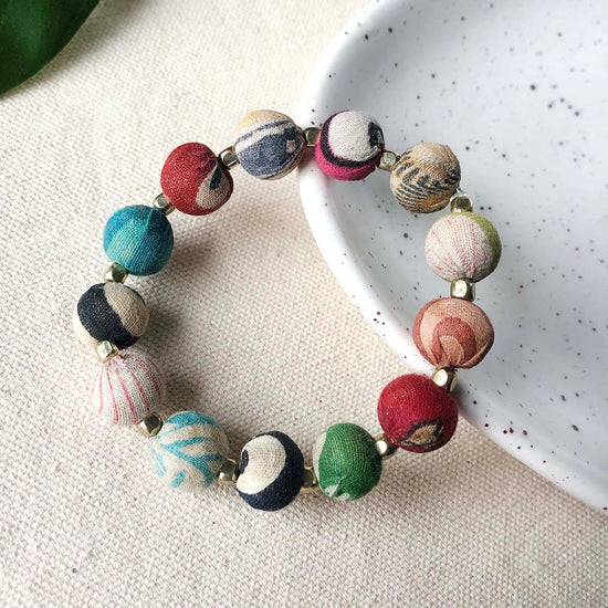 Lifestyle shot of the small bauble bracelet resting partially on a ceramic dish on the left.